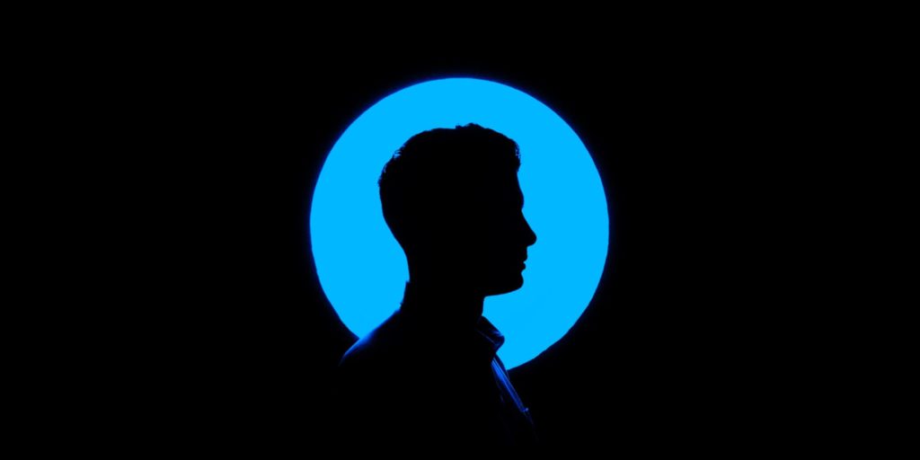 Silhouette of a Man in Front of a Round Blue Light